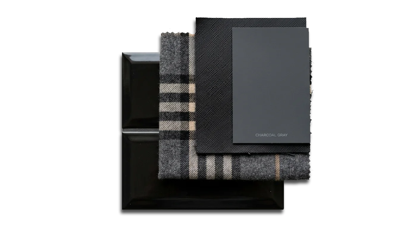 Charcoal gray swatch card layered over plaid fabric and glossy tile samples.